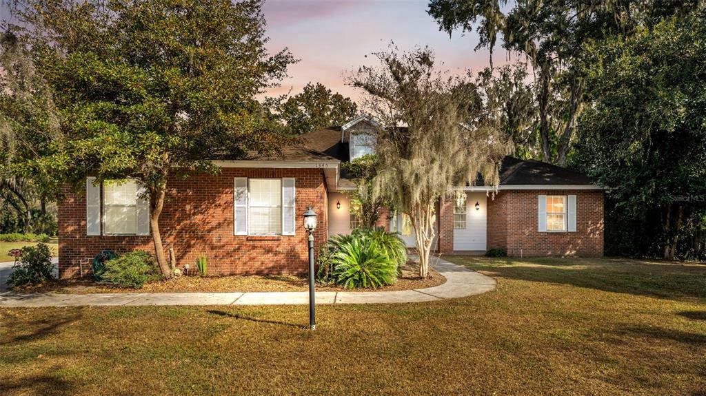 A single-story brick house with a walkway and large trees in the front yard — 1345 LONGOAK DR DRIVE N, LAKELAND, FL