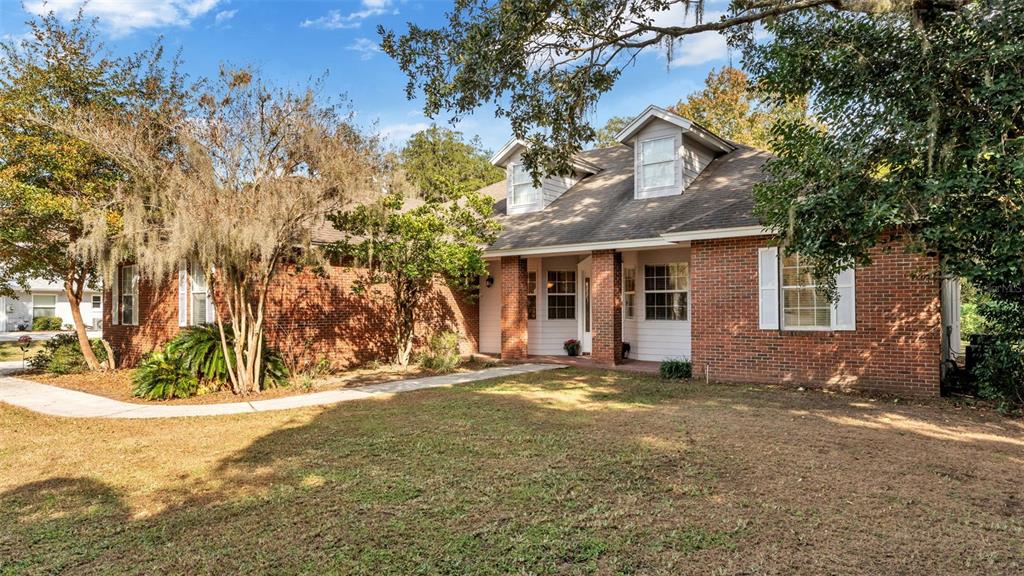 A brick house with a gabled roof and dormer windows sits on a grassy lot — 1345 LONGOAK DR DRIVE N, LAKELAND, FL
