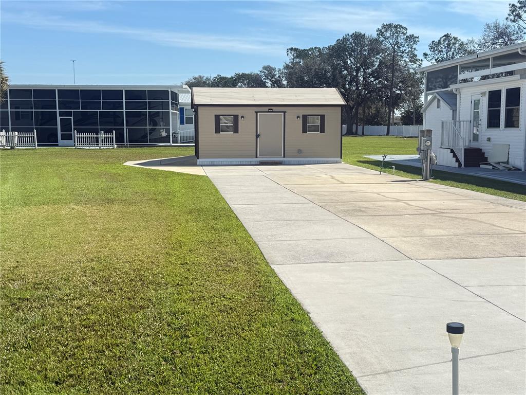 A tan storage shed sits at the end of a concrete driveway between two homes — 8933 SOUTHSHORE COURT, POLK CITY, FL