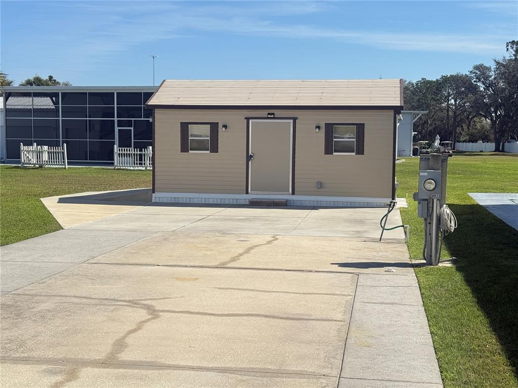 A tan shed with a metal roof and a central door sits on a concrete pad — 8933 SOUTHSHORE COURT, POLK CITY, FL