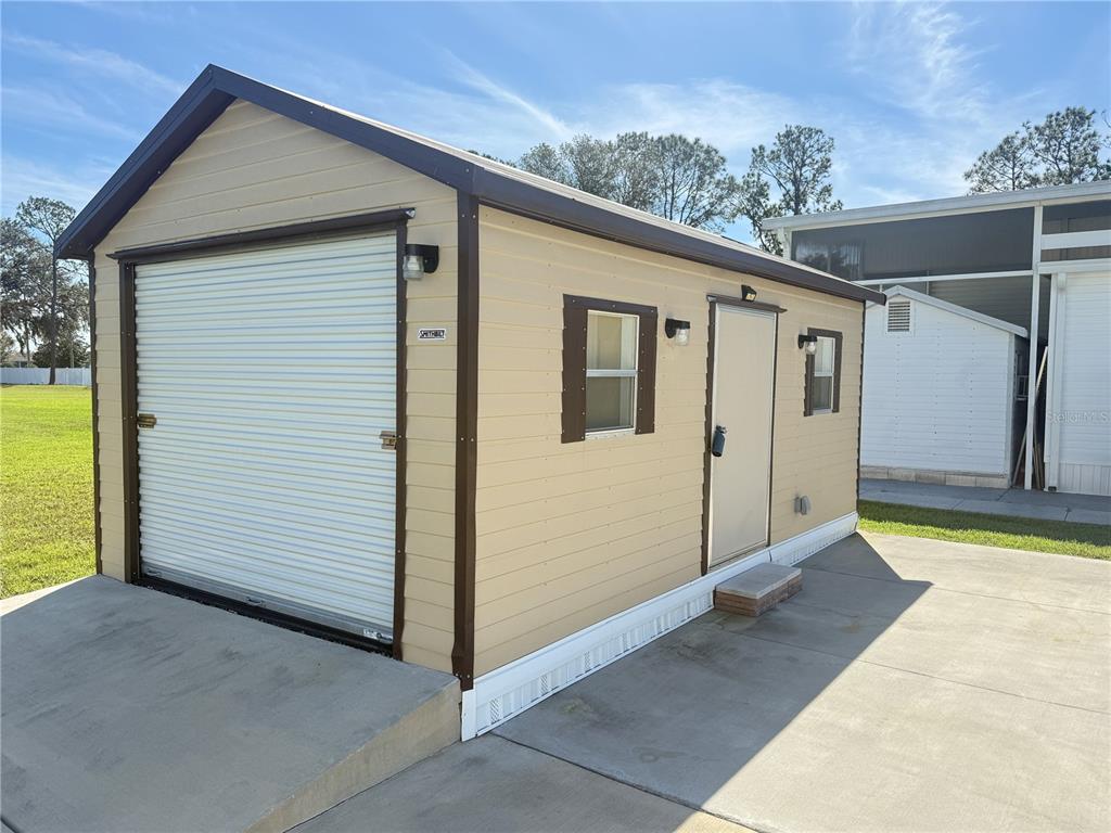 A tan storage shed with a roll-up garage door, a side door, and two windows — 8933 SOUTHSHORE COURT, POLK CITY, FL