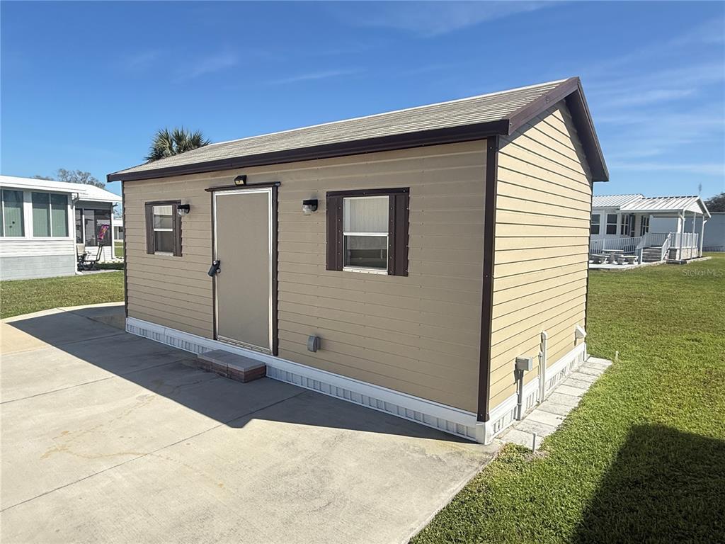 A tan shed with brown trim sits on a concrete pad in a grassy area — 8933 SOUTHSHORE COURT, POLK CITY, FL