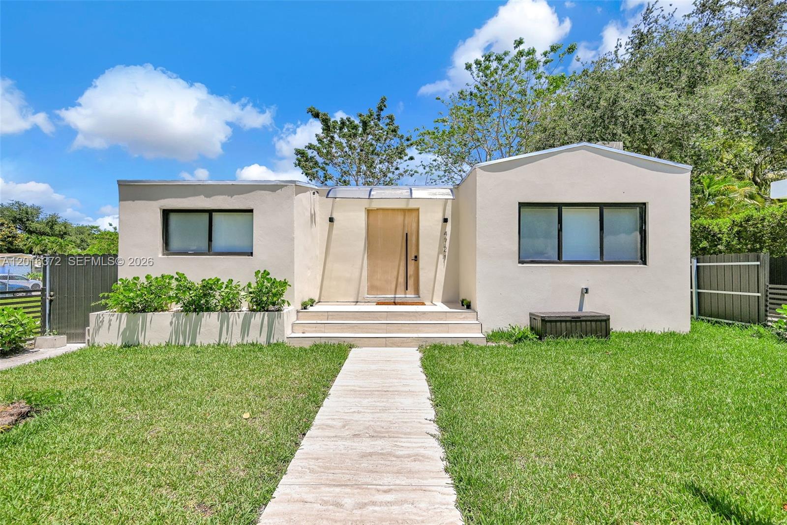 A single-story house with a flat roof, light-colored stucco exterior, and a central wooden door — 4721 NW 6th Ave, Miami FL 33127, MIAMI, FL