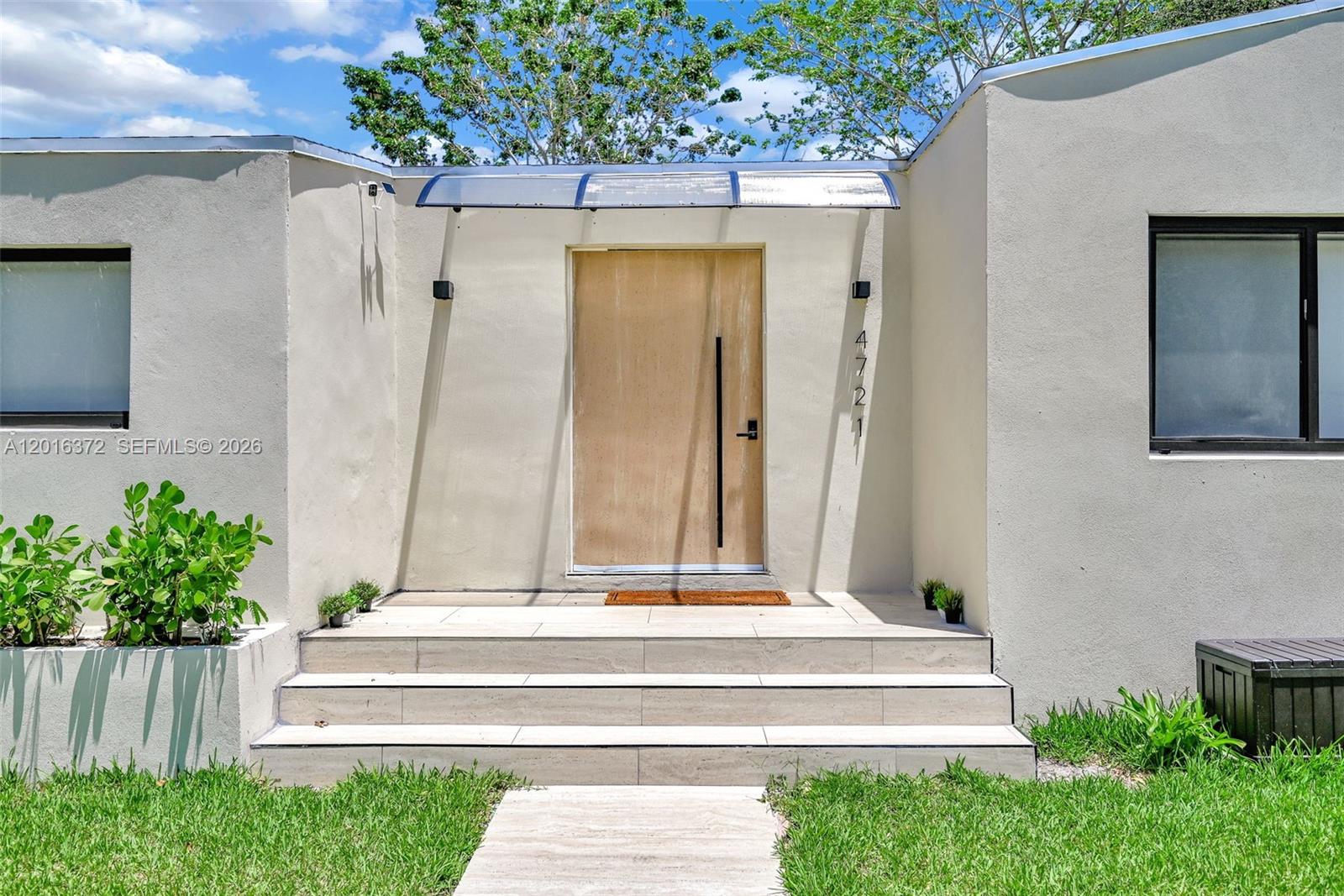 The exterior of a modern home features a light-colored facade, a wooden door, and steps — 4721 NW 6th Ave, Miami FL 33127, MIAMI, FL