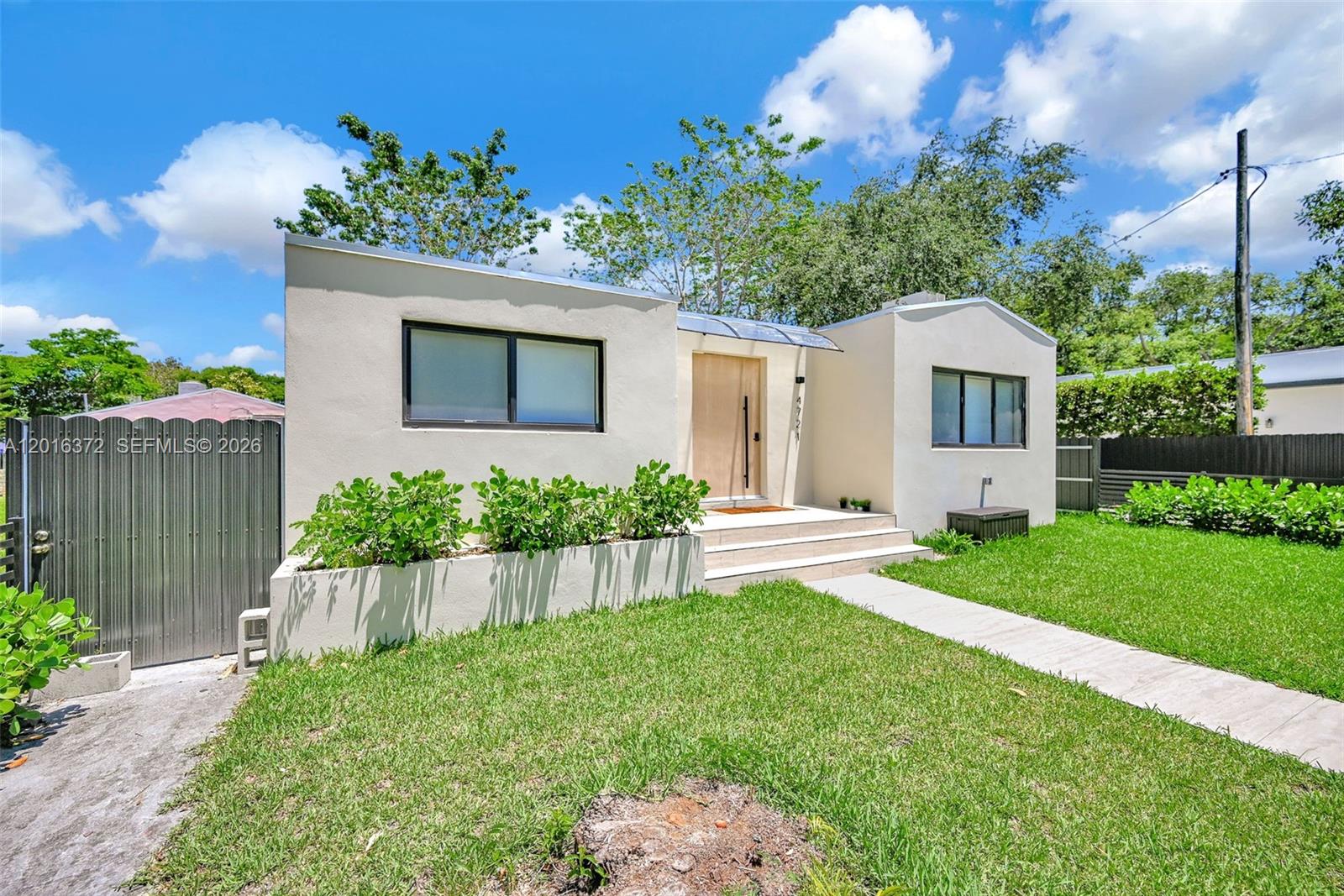 A single-story house with a light-colored stucco exterior, a wooden front door, and landscaping — 4721 NW 6th Ave, Miami FL 33127, MIAMI, FL