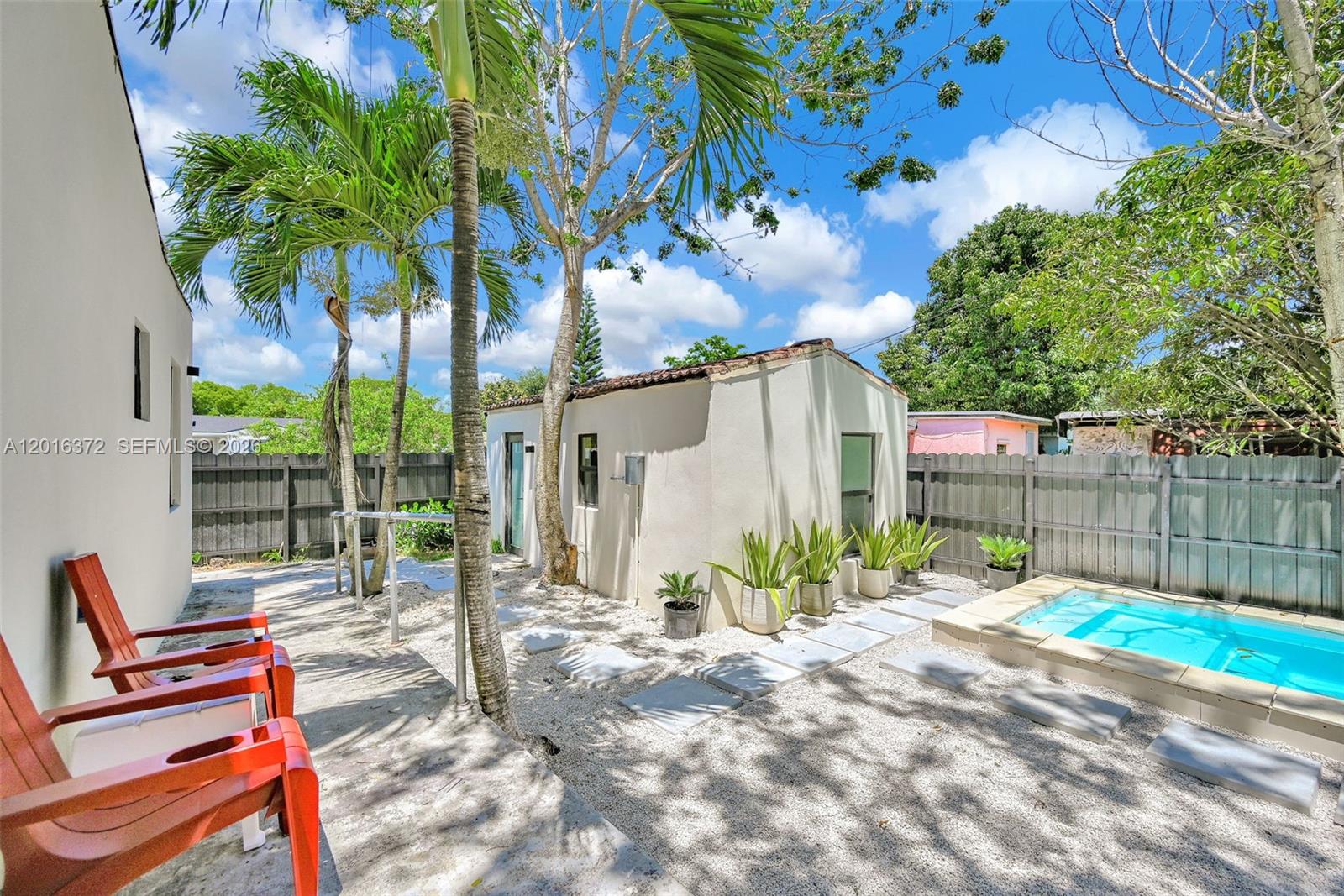 A backyard features a small pool, a detached structure, palm trees, and red chairs — 4721 NW 6th Ave, Miami FL 33127, MIAMI, FL