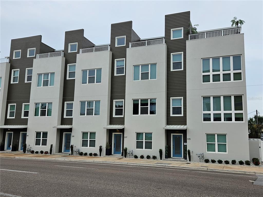 A row of modern, multi-story townhouses features gray siding, white stucco accents, and rooftop terraces — 339 8TH STREET N, ST PETERSBURG, FL