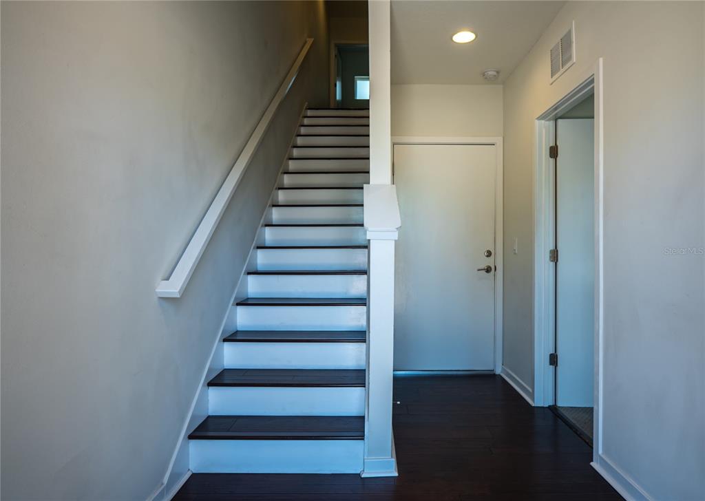 A staircase with dark wood treads and white risers leads to an upper floor — 339 8TH STREET N, ST PETERSBURG, FL