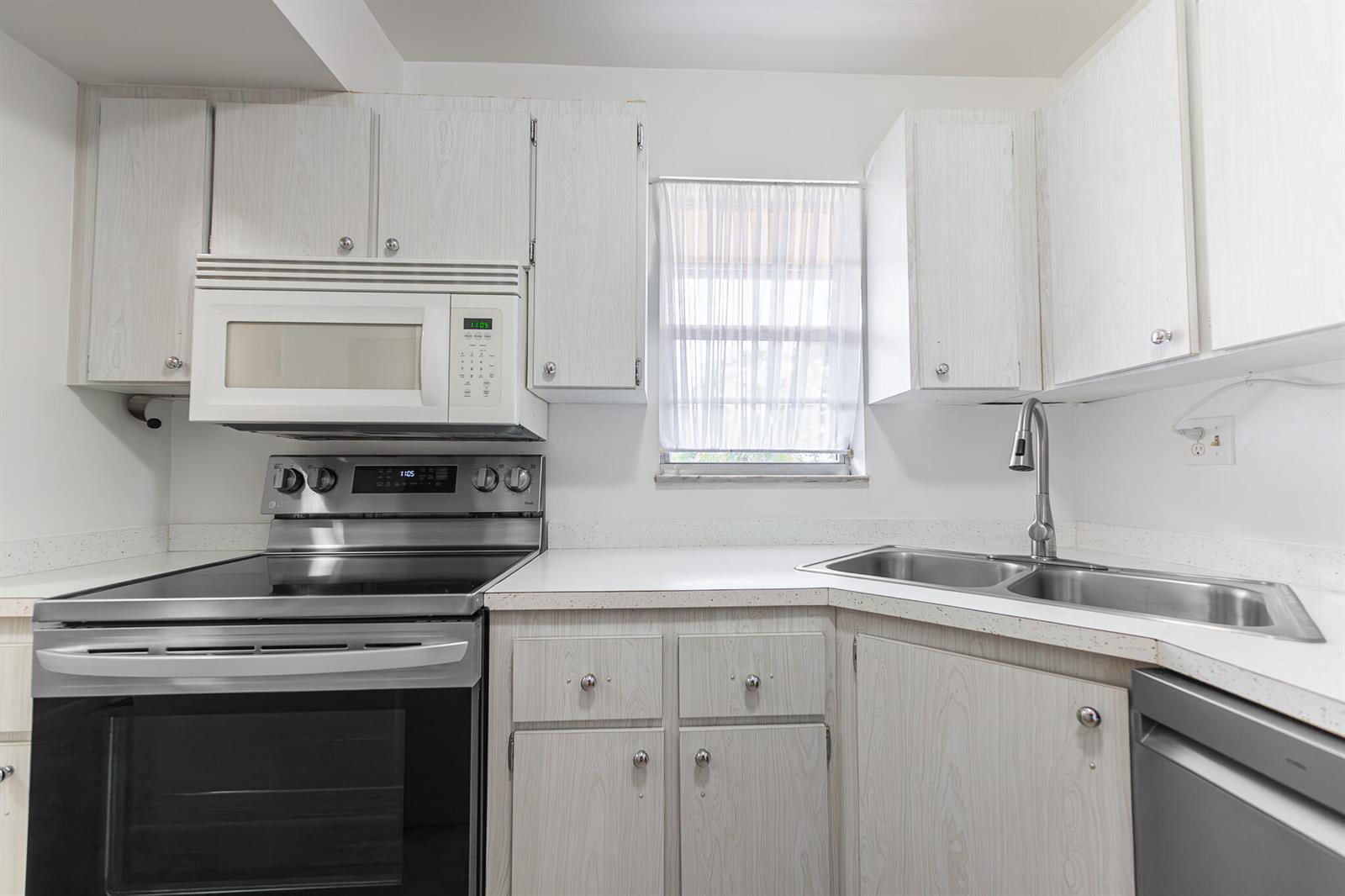 A kitchen features white wood-grain cabinets, stainless steel appliances, and a double-basin sink — 1982 SW Palm City Road # I, Stuart FL 34994, STUART, FL