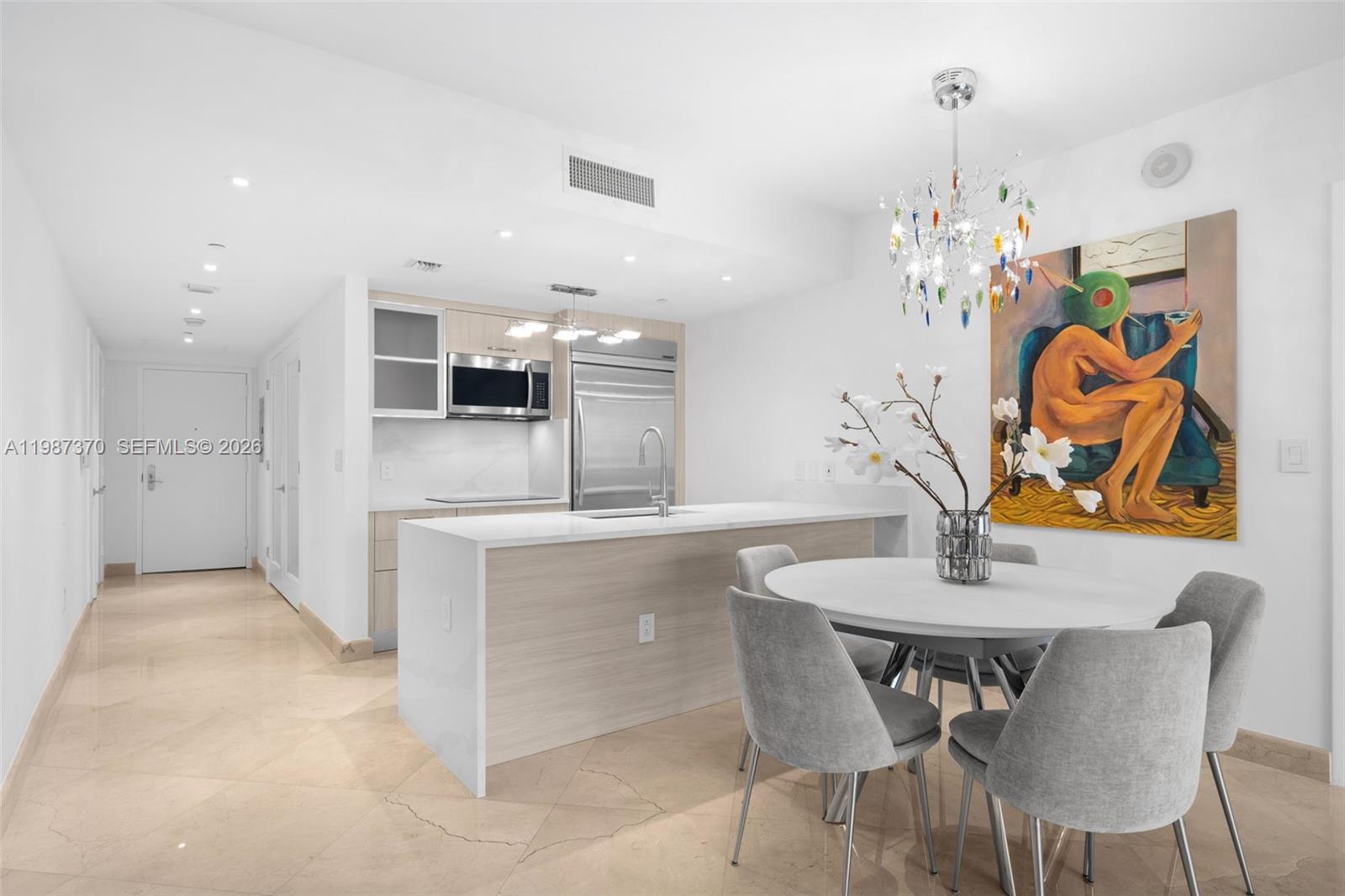 A modern kitchen with a white island and dining area features light wood cabinets — 1850 S Ocean Dr # 4206, Hallandale Beach FL 33009, HALLANDALE BEACH, FL