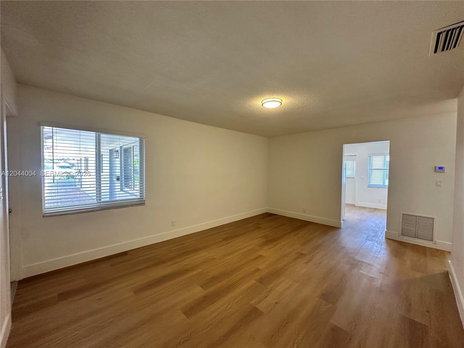 An empty room features light wood-look flooring, white walls, and a window with blinds — 3700 NE 22nd Ave # 4, Lighthouse Point FL 33064, LIGHTHOUSE POINT, FL
