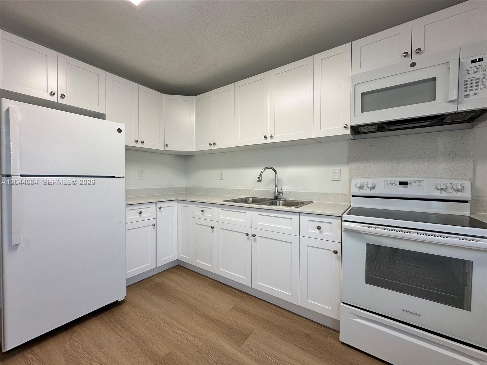 A kitchen features white cabinets, white appliances, a double-basin sink, and light wood-look flooring — 3700 NE 22nd Ave # 4, Lighthouse Point FL 33064, LIGHTHOUSE POINT, FL