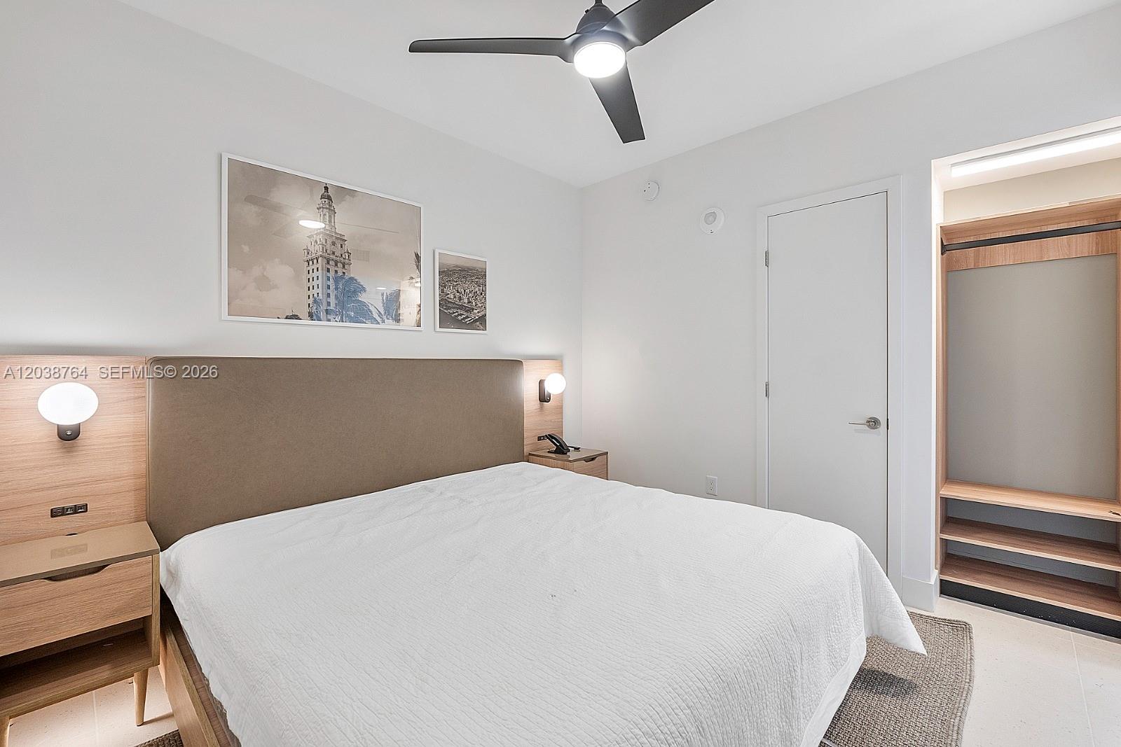 A bedroom features a bed with a tan headboard, wood nightstands, and an open closet — 159 NE 6th St # 2903, Miami FL 33132, MIAMI, FL