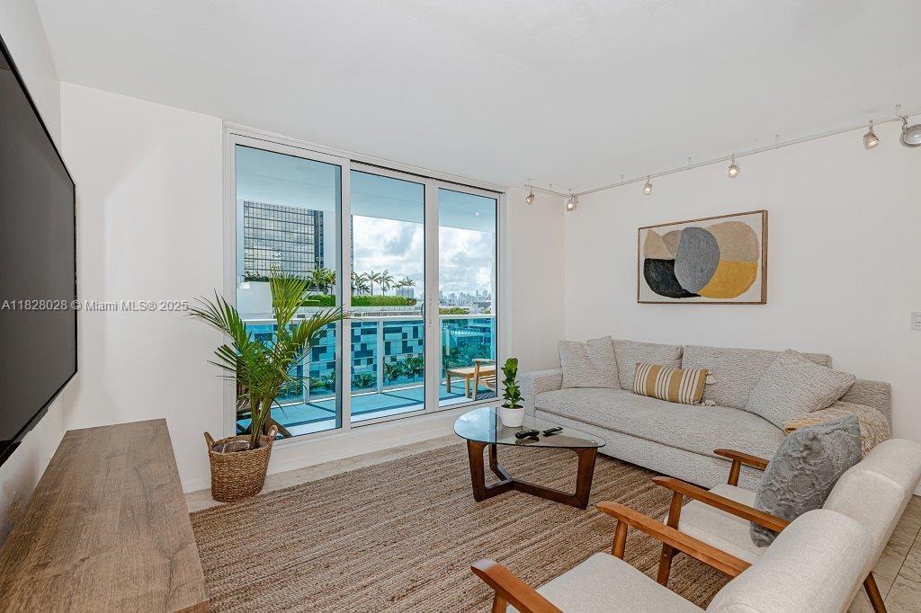 A living room features a sofa, two armchairs, a coffee table, and a balcony view — 2301 Collins Ave # 705, Miami Beach FL 33139, MIAMI BEACH, FL