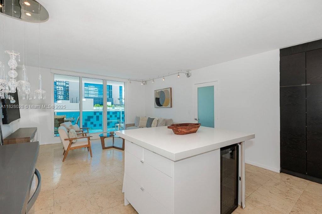 A modern living area features a white kitchen island, tile floors, and a balcony view — 2301 Collins Ave # 705, Miami Beach FL 33139, MIAMI BEACH, FL