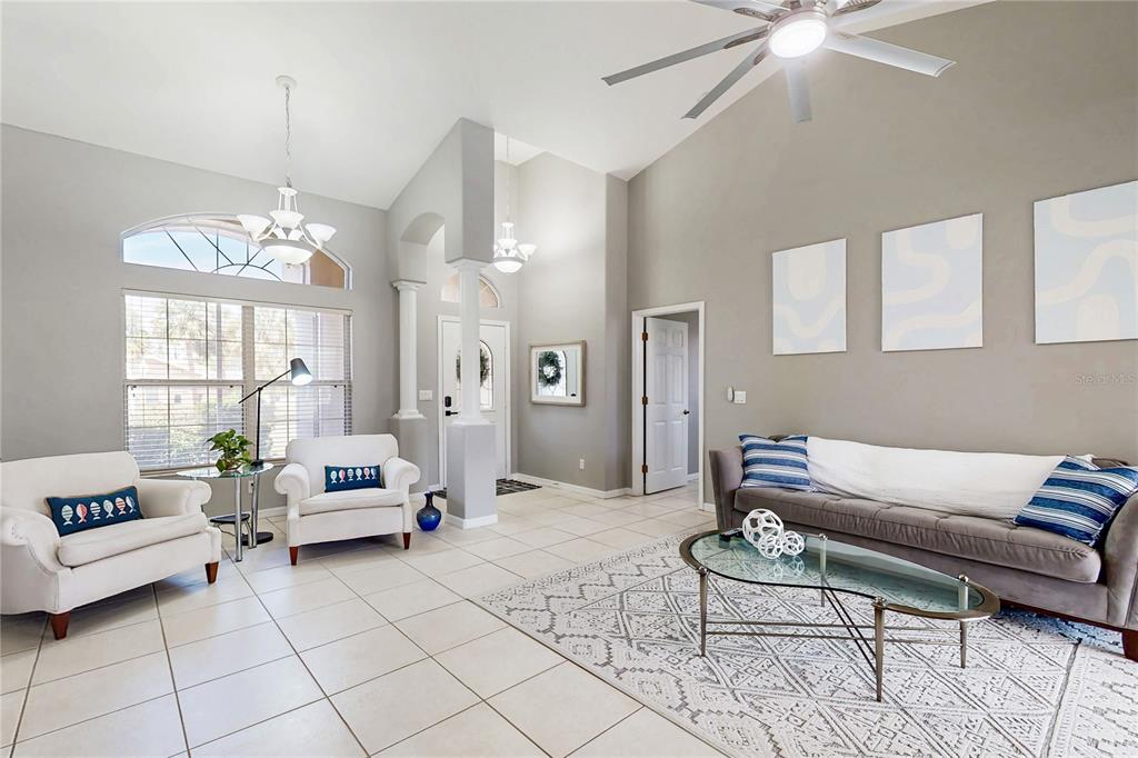 A bright living room features vaulted ceilings, tile flooring, two white armchairs, and a sofa — 1736 NATRONA DRIVE, NORTH PORT, FL
