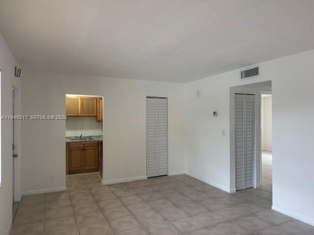An interior view shows a tiled living area with a kitchen and two closet doors — 241 SE 9th Ave # 105, Pompano Beach FL 33060, POMPANO BEACH, FL