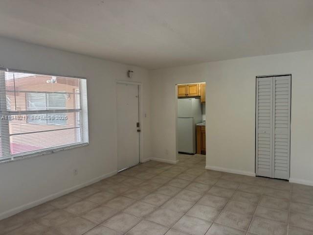 A room with tiled floors, a window with blinds, a door, and a kitchen entrance — 241 SE 9th Ave # 105, Pompano Beach FL 33060, POMPANO BEACH, FL