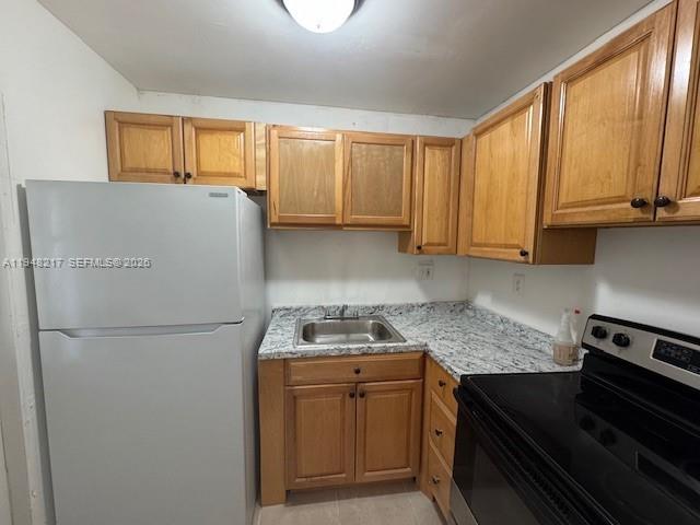 A kitchen features light wood cabinets, a white refrigerator, a black stove, and granite countertops — 241 SE 9th Ave # 105, Pompano Beach FL 33060, POMPANO BEACH, FL