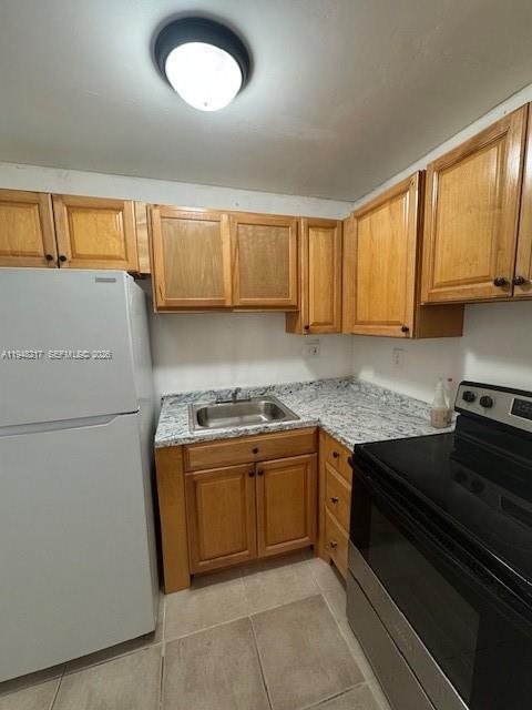 A kitchen features light wood cabinets, granite-look countertops, a white refrigerator, and a black stove — 241 SE 9th Ave # 105, Pompano Beach FL 33060, POMPANO BEACH, FL