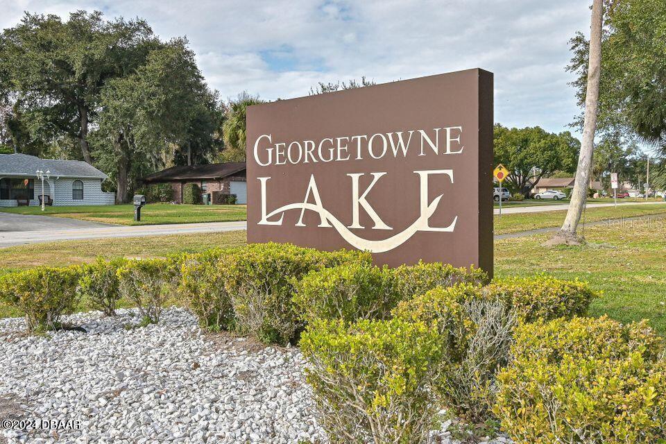 A brown sign for Georgetowne Lake stands in a grassy area with bushes and trees — 1600 BIG TREE ROAD UNIT B7, SOUTH DAYTONA, FL