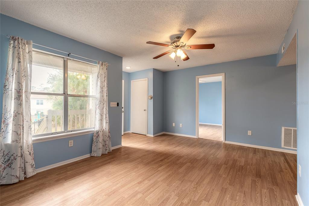 A room with light blue walls, wood-look flooring, a ceiling fan, and a window — 1600 BIG TREE ROAD UNIT B7, SOUTH DAYTONA, FL