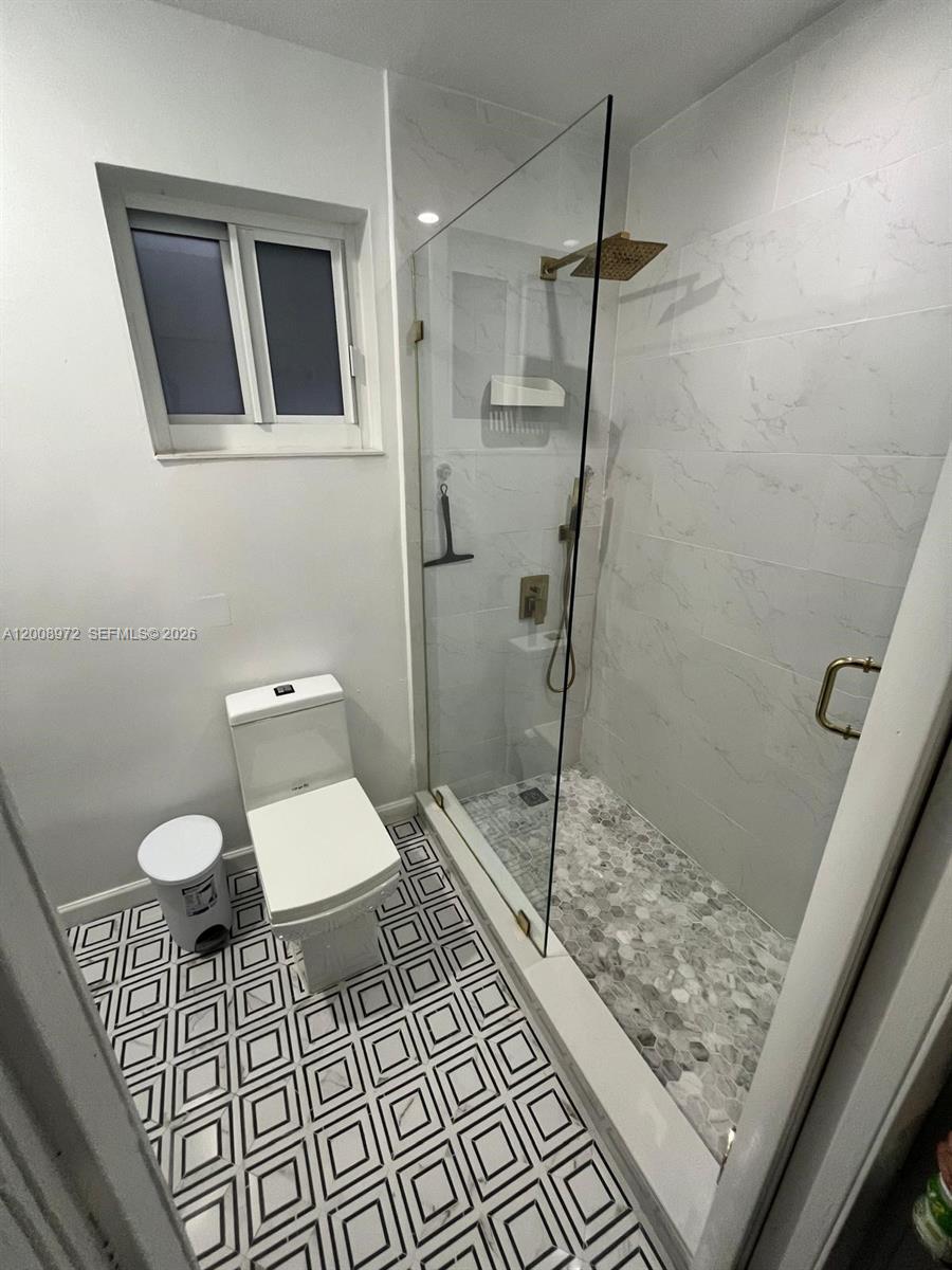 A bathroom features a glass-enclosed shower, a white toilet, and patterned floor tiles — 9704 NW 6th Ter # 9704, Miami FL 33172, MIAMI, FL