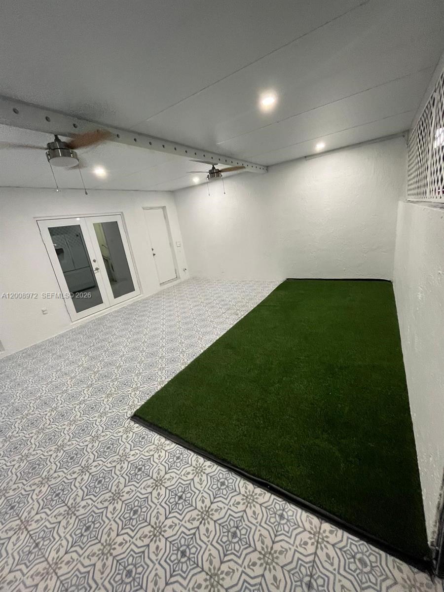 A covered patio features patterned tile flooring, a patch of artificial turf, and ceiling fans — 9704 NW 6th Ter # 9704, Miami FL 33172, MIAMI, FL