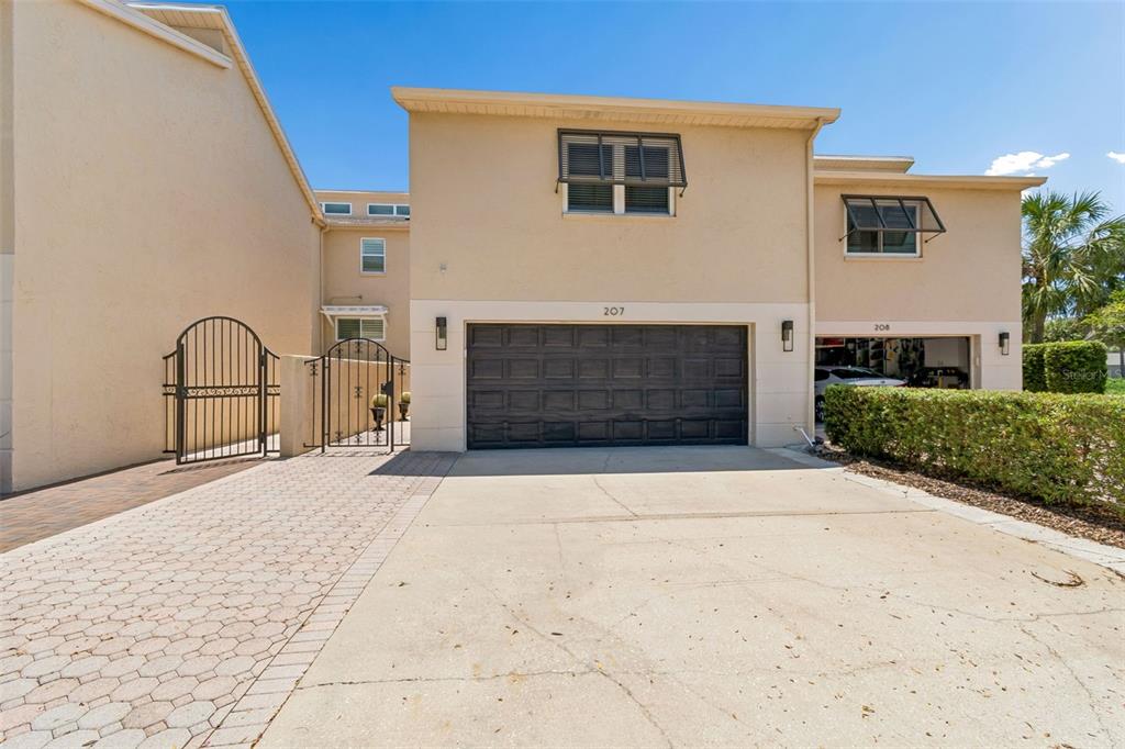 The exterior of a two-story townhouse features a dark garage door and a paved driveway — 487 PINELLAS BAYWAY S UNIT 207, ST PETERSBURG, FL