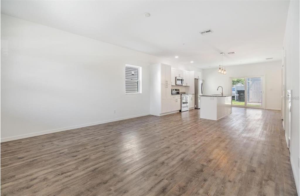 An open-concept kitchen and living area with white cabinets, a kitchen island, and wood flooring — 1264 PIERCE STREET, CLEARWATER, FL