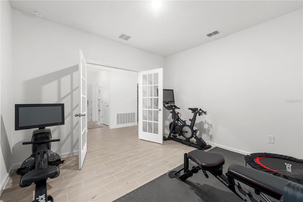 A living room features a large sectional sofa, a wooden hutch, and tile flooring — 13941 NW CONVERGENCE BOULEVARD, ALACHUA, FL