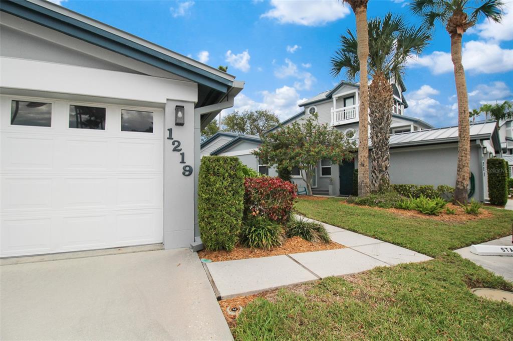 A view of a house exterior featuring a garage, a walkway, and two palm trees — 1219 SIESTA BAYSIDE DRIVE UNIT 1219-C, SARASOTA, FL