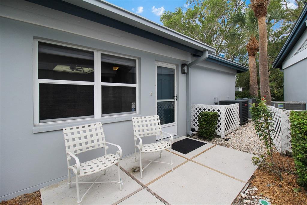 A light gray house exterior features a concrete patio with two white metal chairs — 1219 SIESTA BAYSIDE DRIVE UNIT 1219-C, SARASOTA, FL