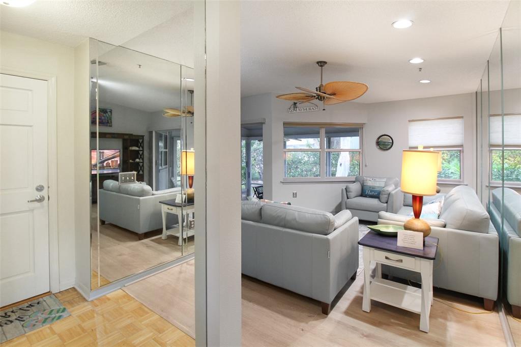 A living room features light blue sofas, a ceiling fan, and mirrored wall panels — 1219 SIESTA BAYSIDE DRIVE UNIT 1219-C, SARASOTA, FL