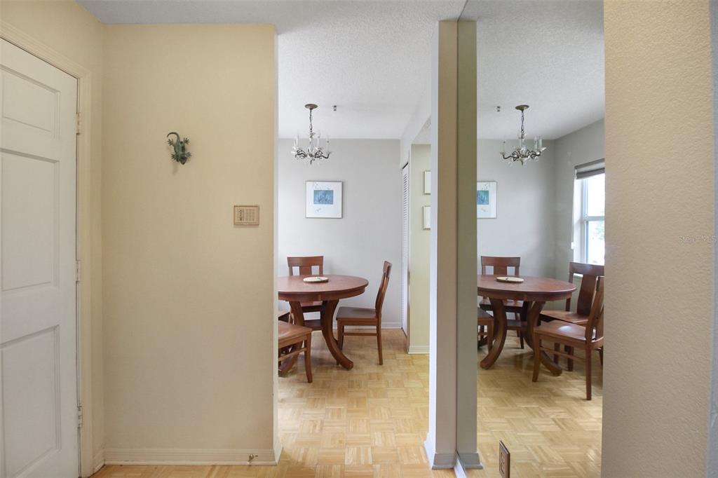A dining room with a round wooden table and chairs is reflected in a mirrored wall — 1219 SIESTA BAYSIDE DRIVE UNIT 1219-C, SARASOTA, FL