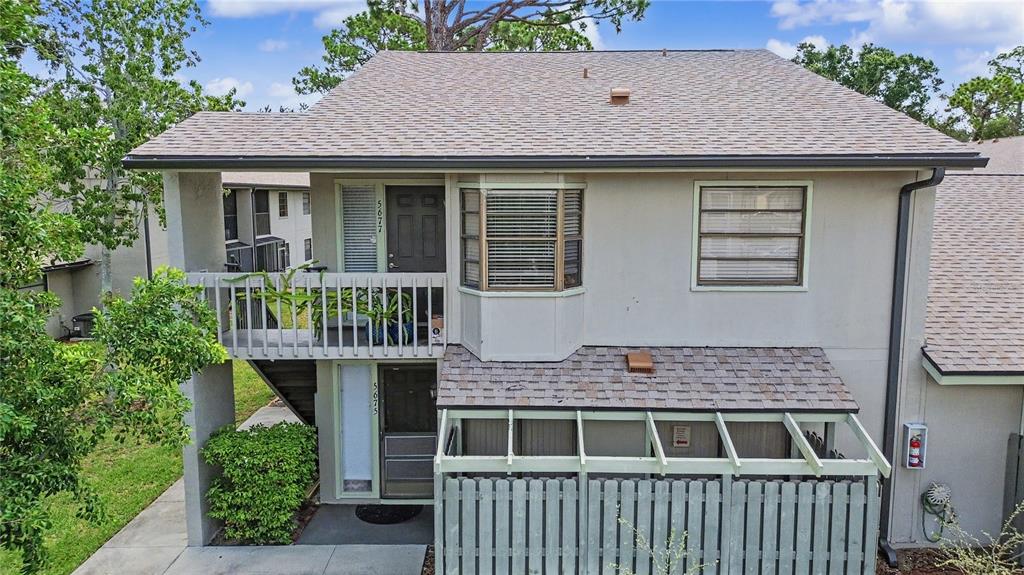 A two-story building exterior features a ground-level patio with a fence and an upper-level balcony — 5677 SUMMER SIDE LANE UNIT 31B, SARASOTA, FL