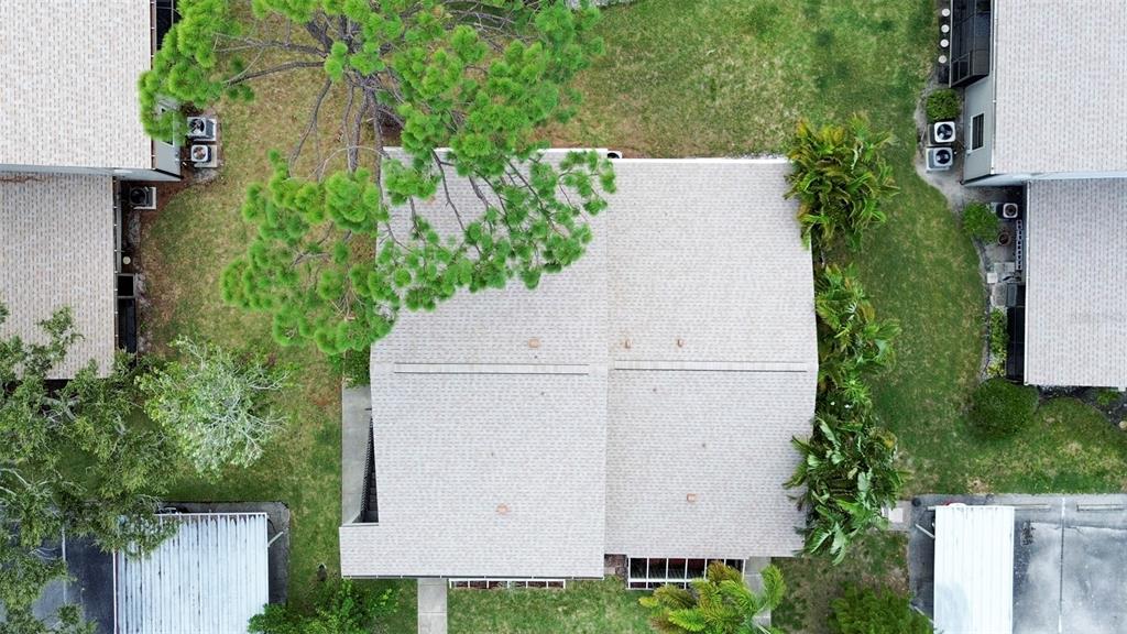An aerial view shows the shingled roof of a residential building surrounded by green landscaping — 5677 SUMMER SIDE LANE UNIT 31B, SARASOTA, FL