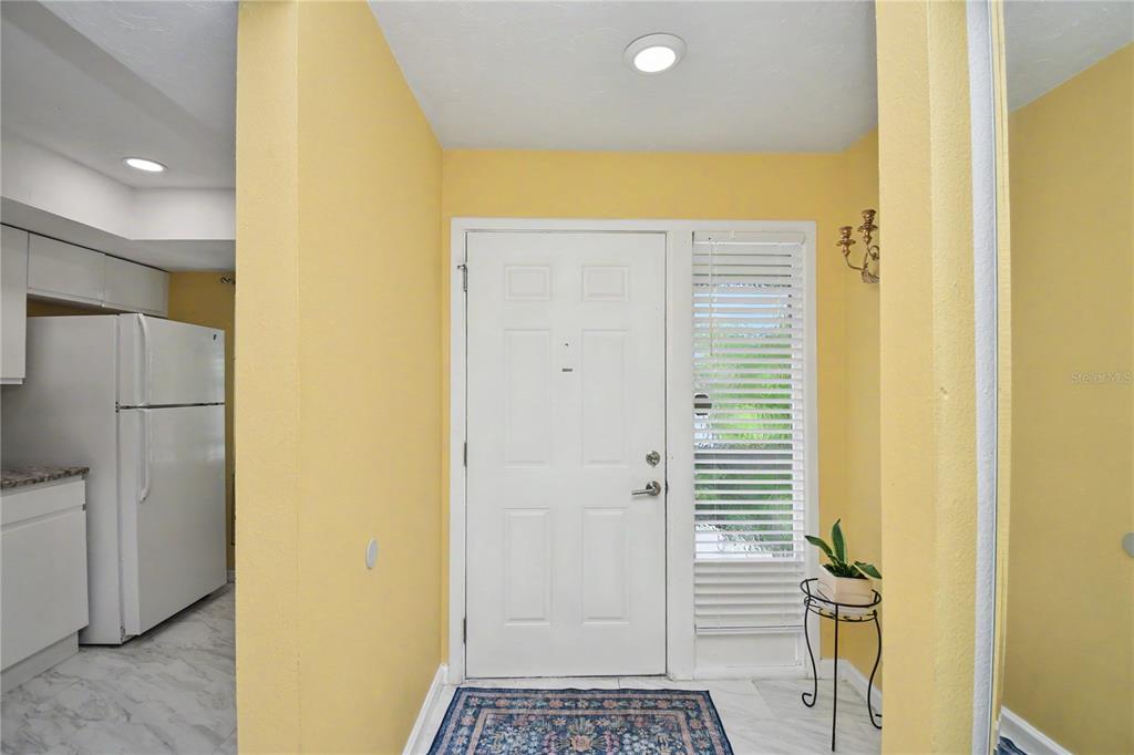 An entryway with yellow walls, a white front door, and a tiled floor — 5677 SUMMER SIDE LANE UNIT 31B, SARASOTA, FL