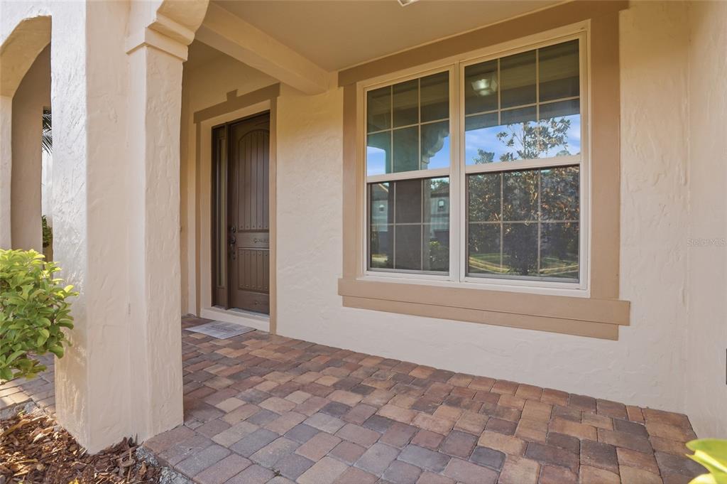 A covered entryway features a paver floor, a brown front door, and a large window — 2330 KELBROOK COURT, OVIEDO, FL