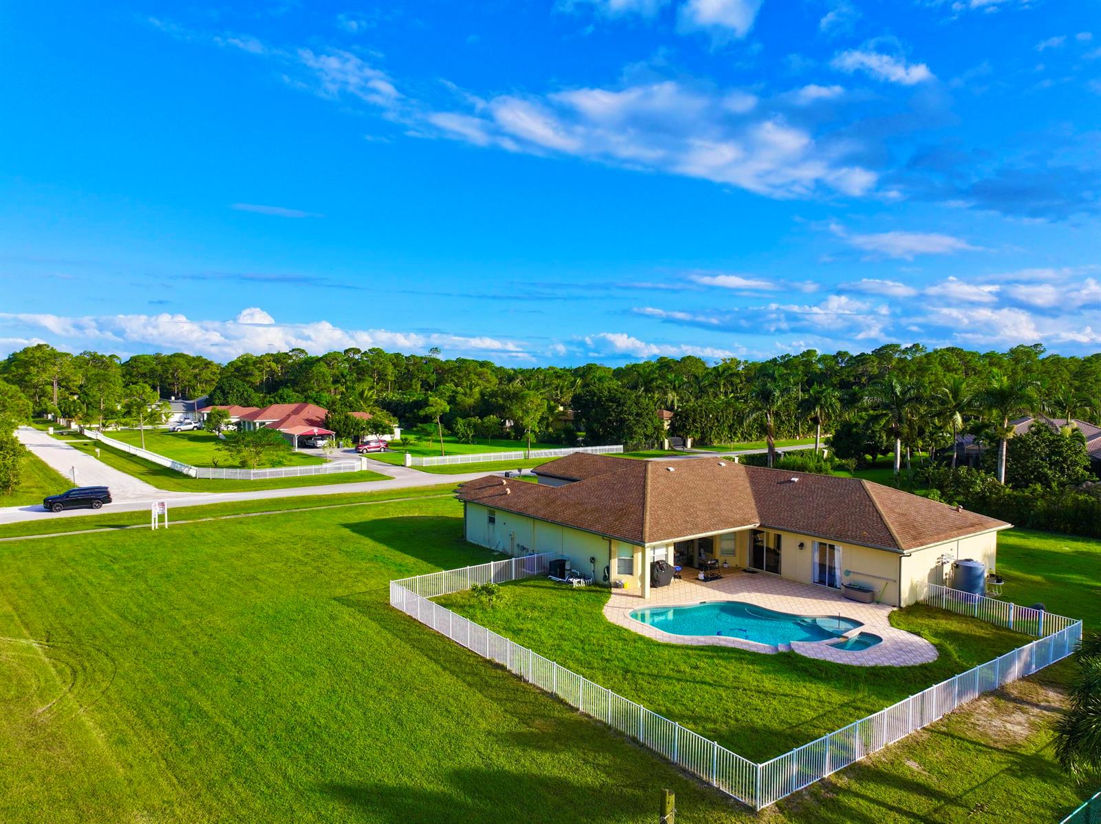 An aerial view shows a house with a pool, fenced yard, and surrounding landscape — 6613 Hall Boulevard, FL 33470, FL