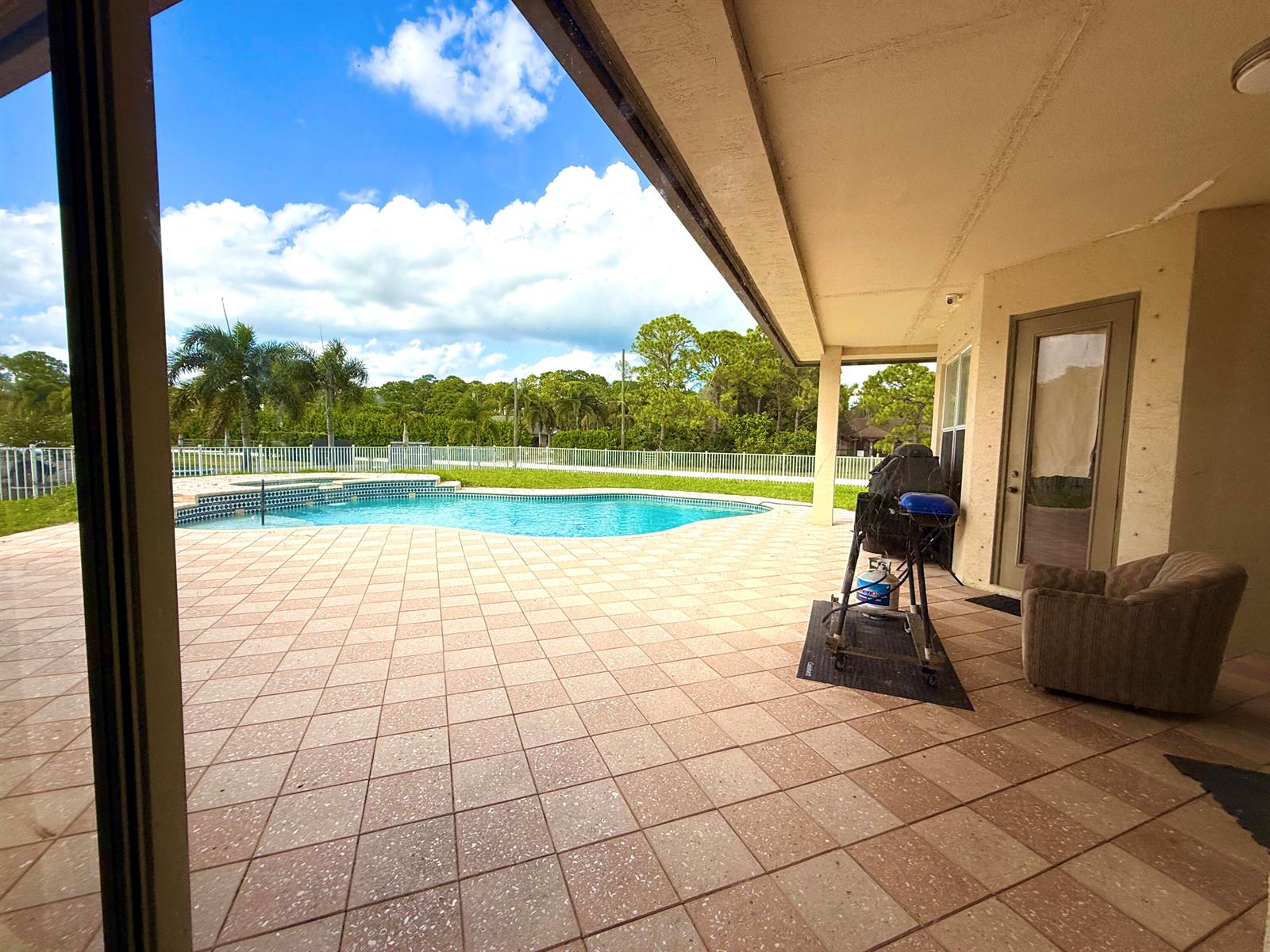 A covered patio features tiled flooring, a swimming pool, and a view of the backyard — 6613 Hall Boulevard, FL 33470, FL