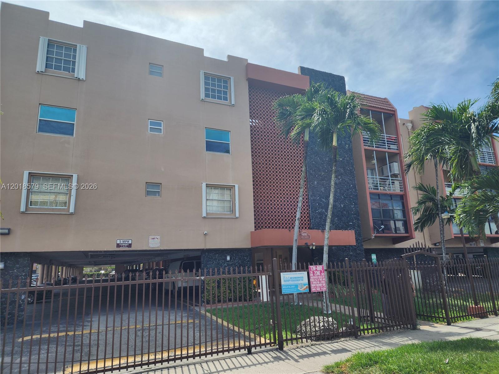 A multi-story apartment building features a tan facade, a decorative screen, and a gated parking area — 6095 W 19th Ave # 205, Hialeah FL 33012, HIALEAH, FL
