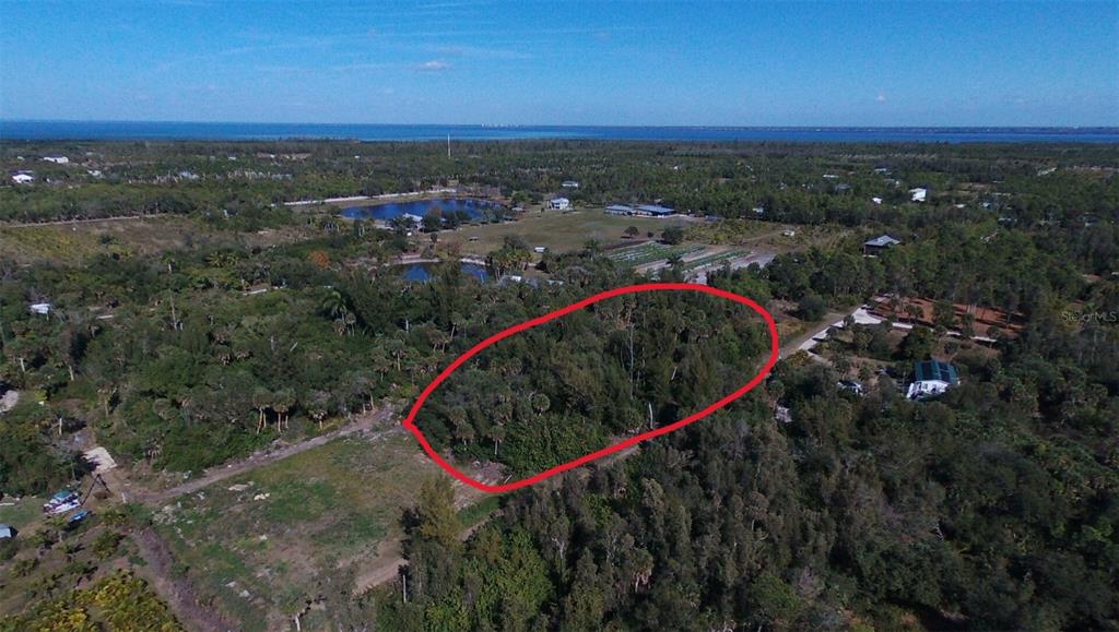 An aerial view shows a wooded lot outlined in red within a rural landscape — 7224 COCCOLOBA WAY, BOKEELIA, FL