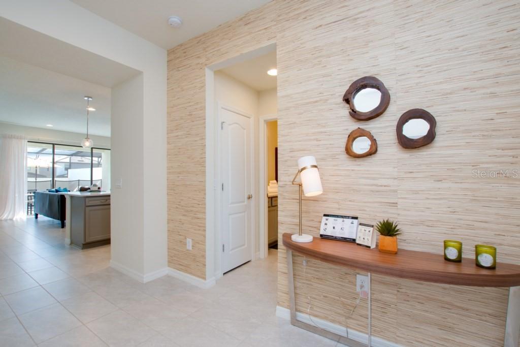 A hallway features textured wallpaper, a curved console table, and three circular wall mirrors — 8916 SYDNEY AVENUE, KISSIMMEE, FL