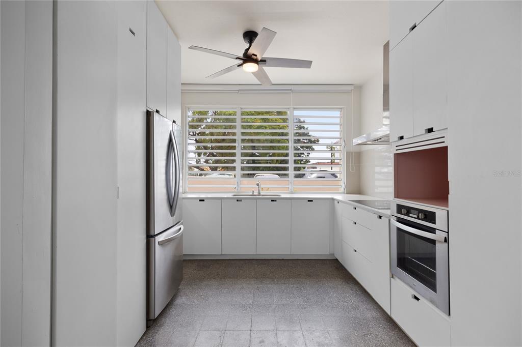A modern kitchen features white cabinetry, stainless steel appliances, and louvered windows — K1 AVE. LUIS VIGOREAUX UNIT k, GUAYNABO, PR