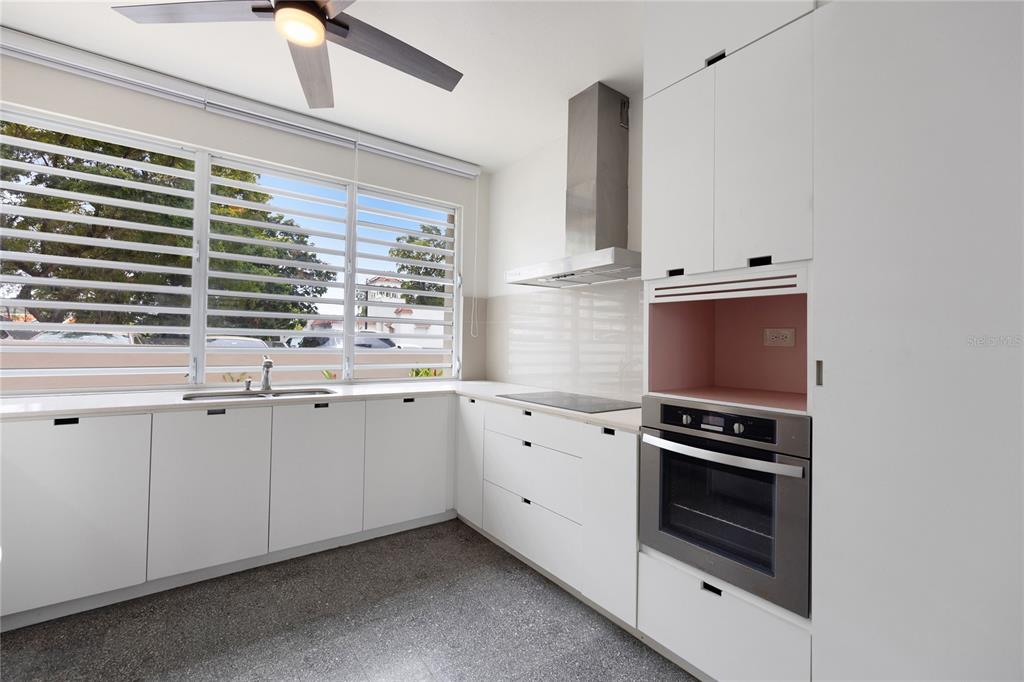 A modern kitchen features white cabinetry, stainless steel appliances, and large louvered windows — K1 AVE. LUIS VIGOREAUX UNIT k, GUAYNABO, PR