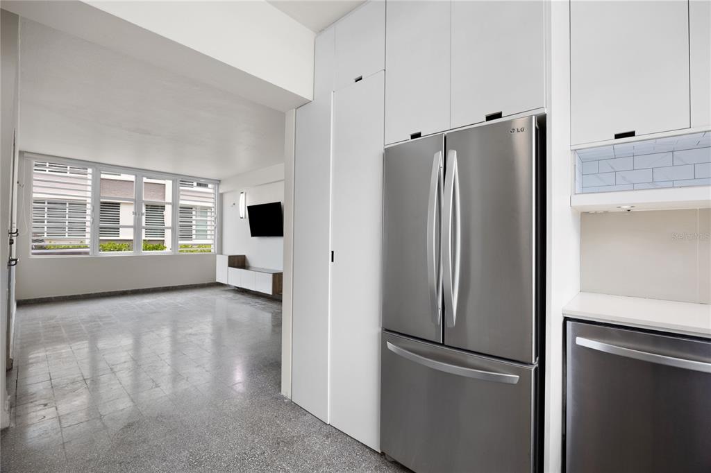 A kitchen with stainless steel appliances and white cabinetry opens into a living area — K1 AVE. LUIS VIGOREAUX UNIT k, GUAYNABO, PR