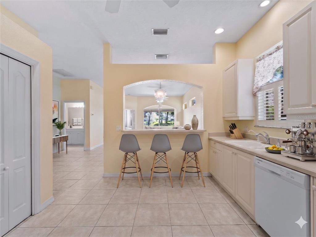 A kitchen with light-colored cabinets, a breakfast bar with three stools, and tile flooring — 2189 LYNX RUN UNIT 2189, NORTH PORT, FL