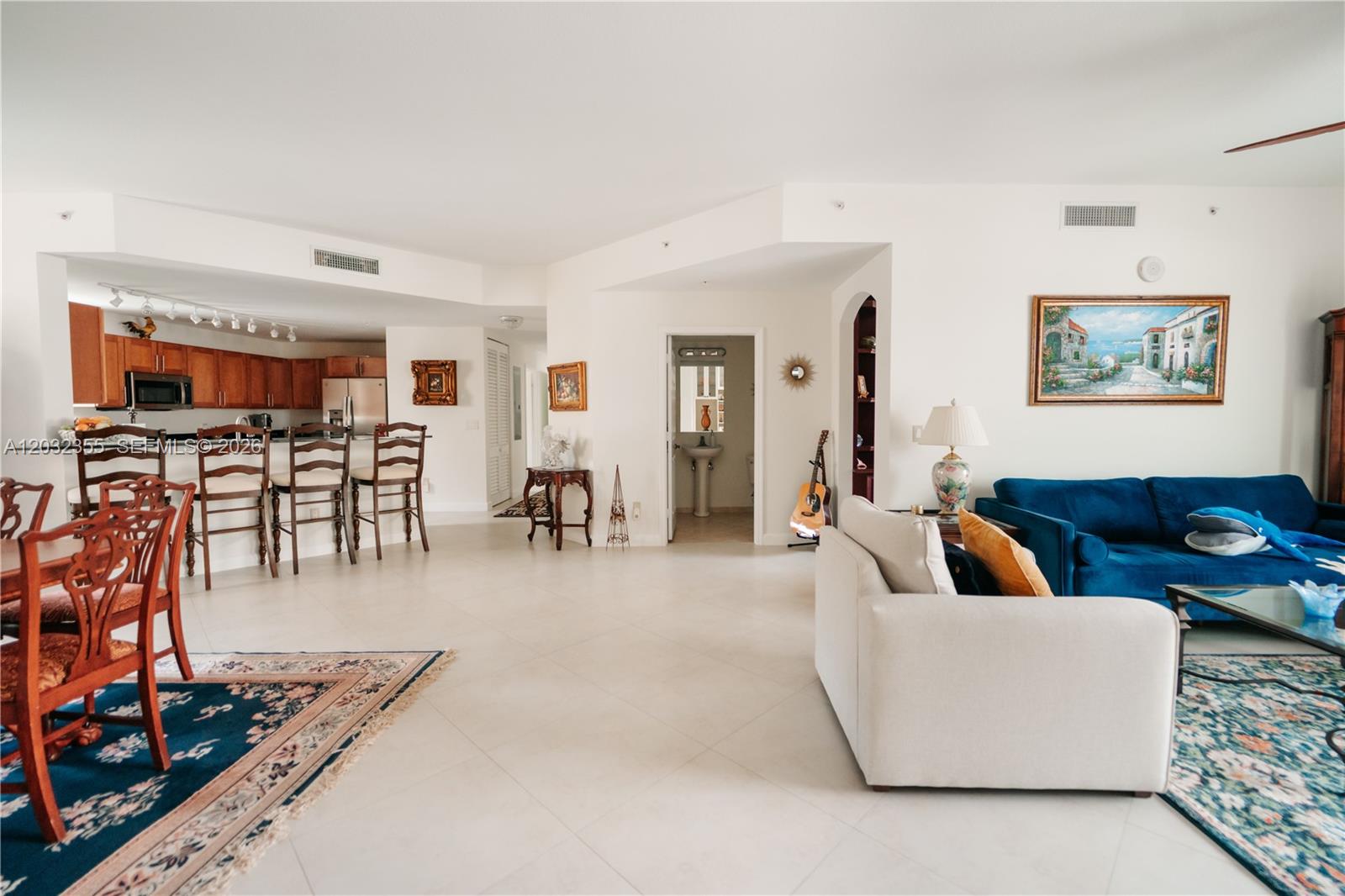 A living room features a blue sofa, two white armchairs, a glass coffee table, and a ceiling fan — 8390 SW 72nd Ave # 707, Miami FL 33143, MIAMI, FL