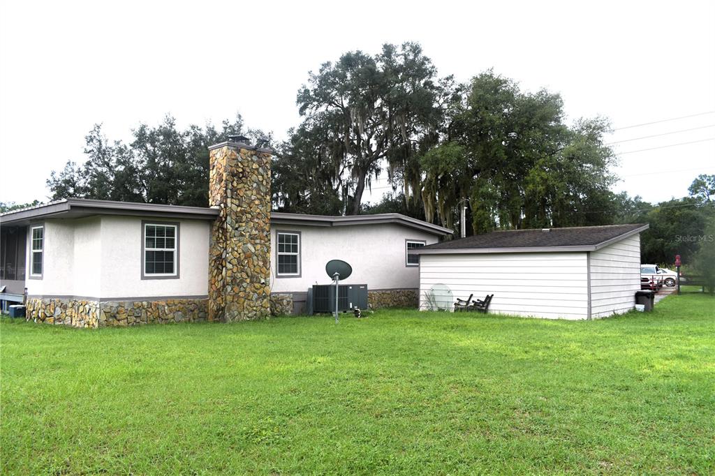 The exterior of a single-story house features a stone chimney and an attached garage — 15355 SW 85TH AVENUE, DUNNELLON, FL